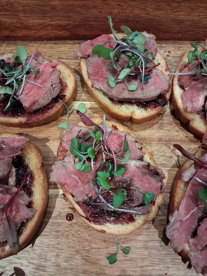 Beef crostini with microgreens on wooden board